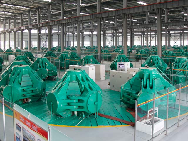 A large industrial facility housing multiple green, high-pressure cubic machines used for the production of synthetic diamonds.